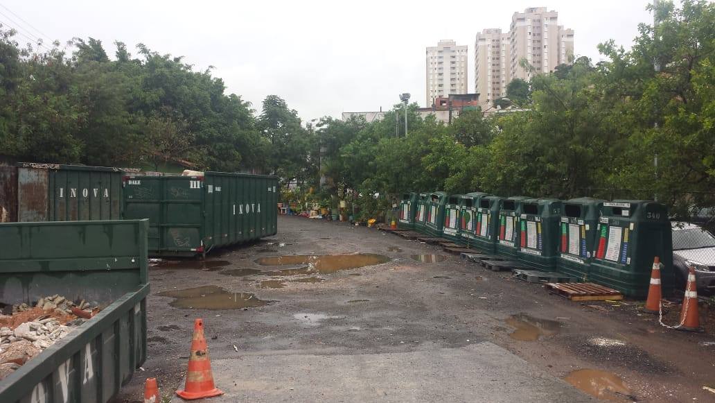 Na imagem estão as lixeiras para coleta seletiva e as caçambas para entulhos, todas na cor verde escuro.